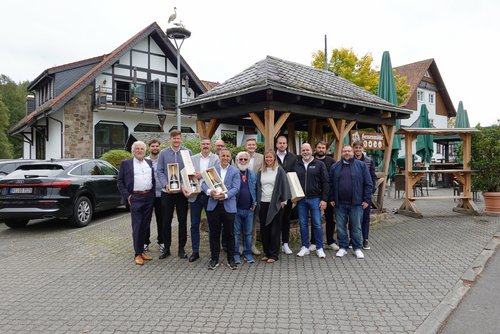TUBELESS-Gesellschafter stehen vor einem Fachwerkhaus, ein paar halten Champagnerflaschen in den Händen